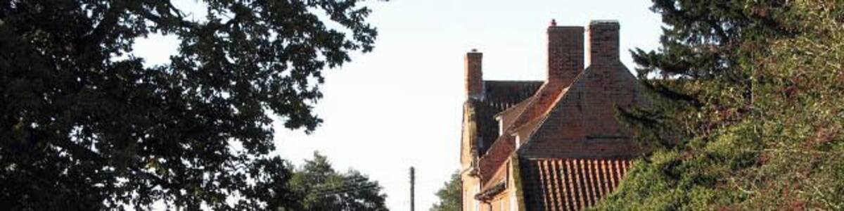 Approaching Manor House Farm. Past the farmhouse seen at right the track/public footpath > 1026019 meets the public road. Manor Farmhouse is described by Pevsner as an unusually perfect example of a late C17 house, dated 1707; for another view see > 205574. (N. Pevsner & B. Wilson, The Buildings of England, Norfolk 1, 2002).