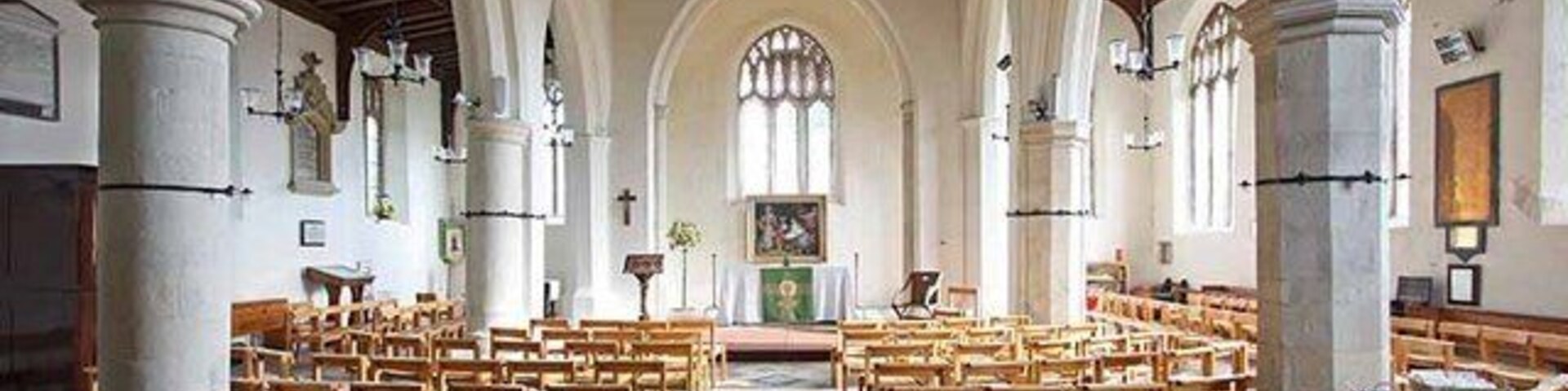 Interior de una iglesia con bancas de madera, techos abovedados y suelo de baldosas.