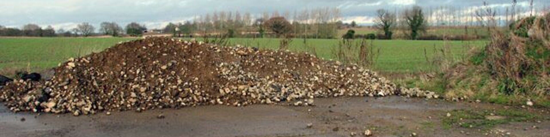 View north across cultivated field. The line of poplars seen in the background denote the course of King's Beck which flows into the River Bure a short distance further to the southeast. North Farm > 451507 - in adjacent grid square to the northwest - can just be glimpsed above the top of the heap of rubble which has been deposited at the edge of the concrete farm hardstand seen in the foreground.