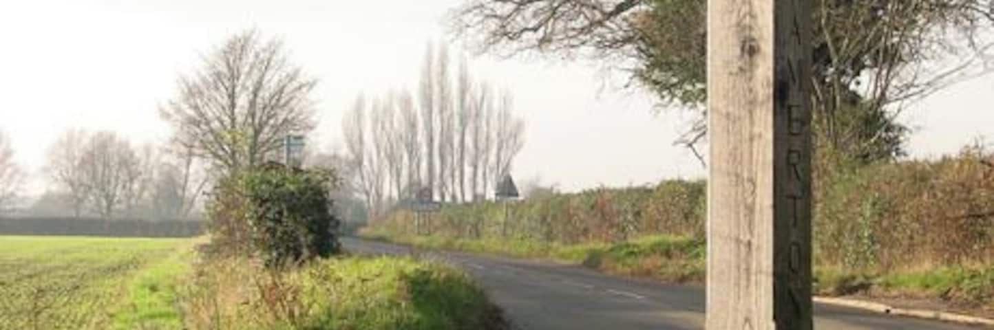 View west along Kirby Road past Bramerton village sign The village sign is situated on a small triangular green by the junction of Surlingham and Kirby Road.