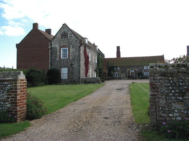 Entrance to the Hall. Waxham Hall is a 12th century manor which by the 16th century was owned by the Calthorpe family and later by the Wodehouses, who built the Hall and its enclosure, presumably before the death of Sir Thomas in 1571. The house was surrounded by a high wall entered through gateways - with tracery in the spandrels > 995305 - which originally extended outwards to include the church. The enclosing wall has polygonal angle buttress shafts which are crowned by finials. (N. Pevsner & B. Wilson, The Buildings of England, Norfolk 1, 2002)