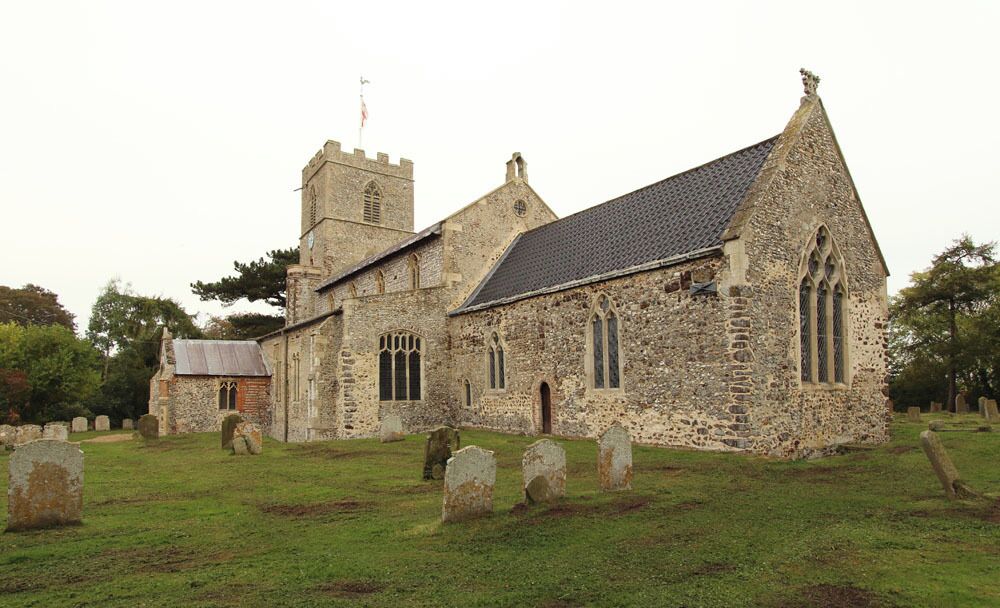A historic stone church with a bell tower and a graveyard.