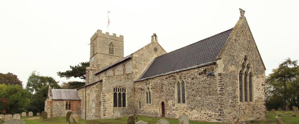 A historic stone church with a bell tower and a graveyard.