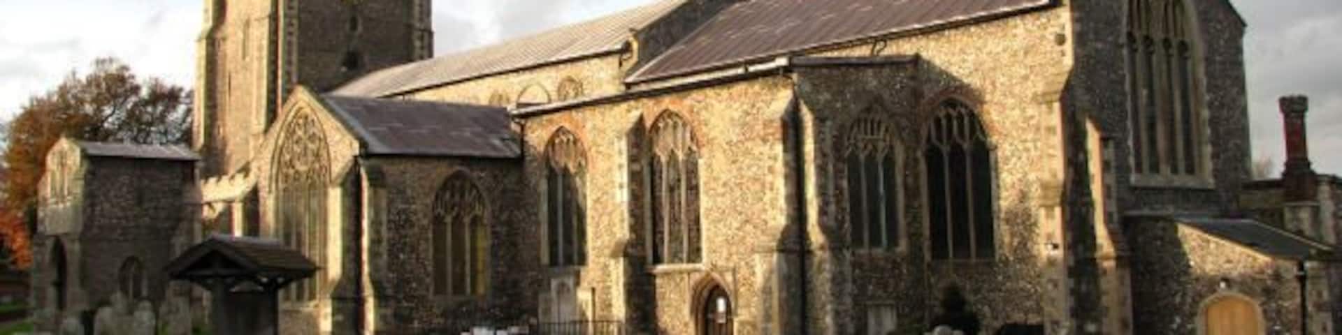 A historic church with a tall tower and a graveyard in front.