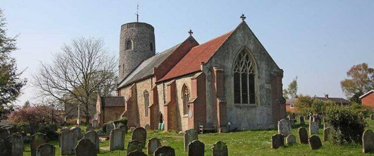 A church with a tower and a graveyard in front.