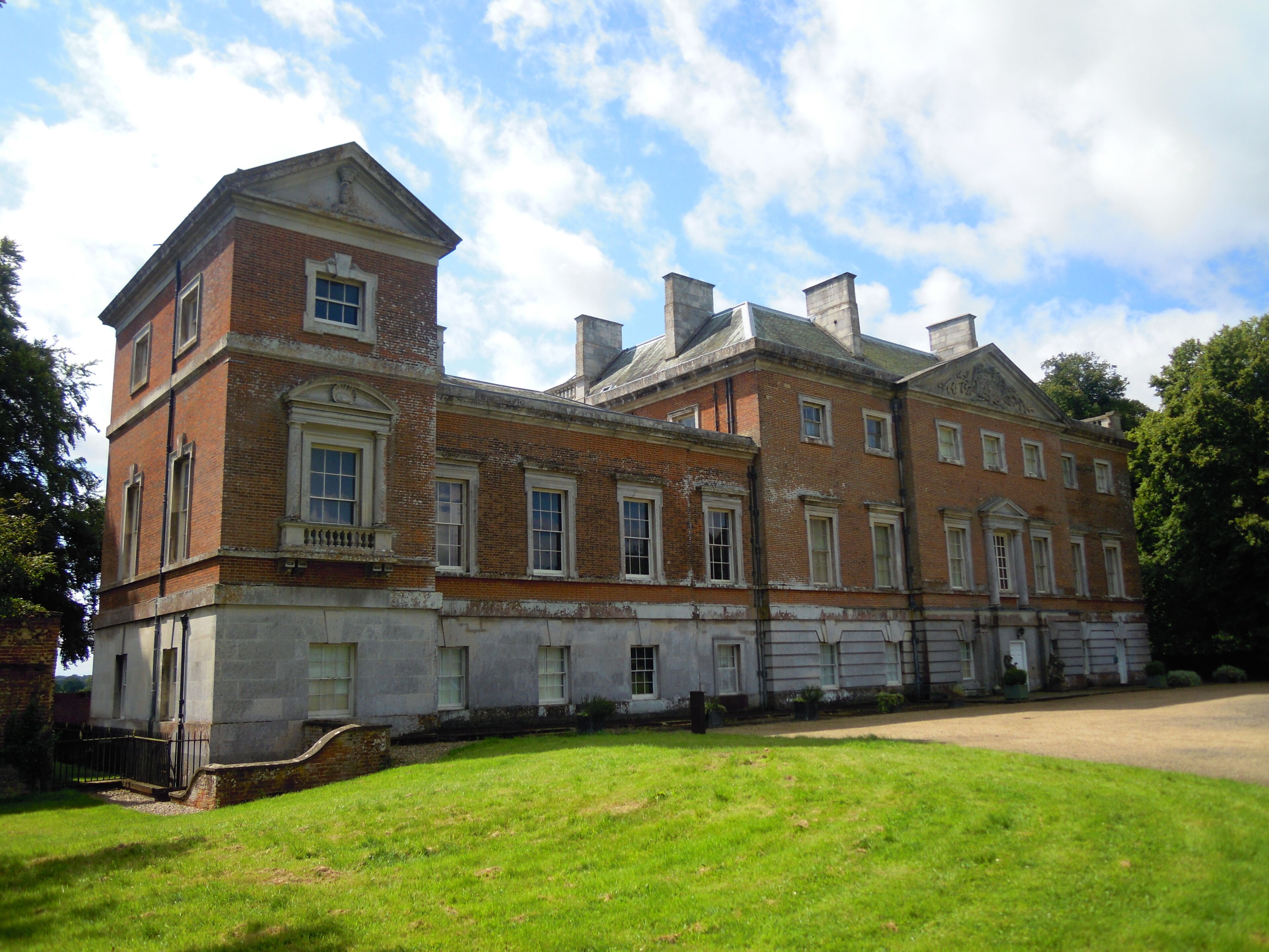 A large, historic brick building with multiple chimneys and a prominent tower.