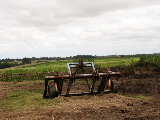 Parked implement The view is north, towards Aylsham. The tower of St Michael's church, Aylsham, can be seen on the horizon (across the fields, above the right wheel of the parked implement).