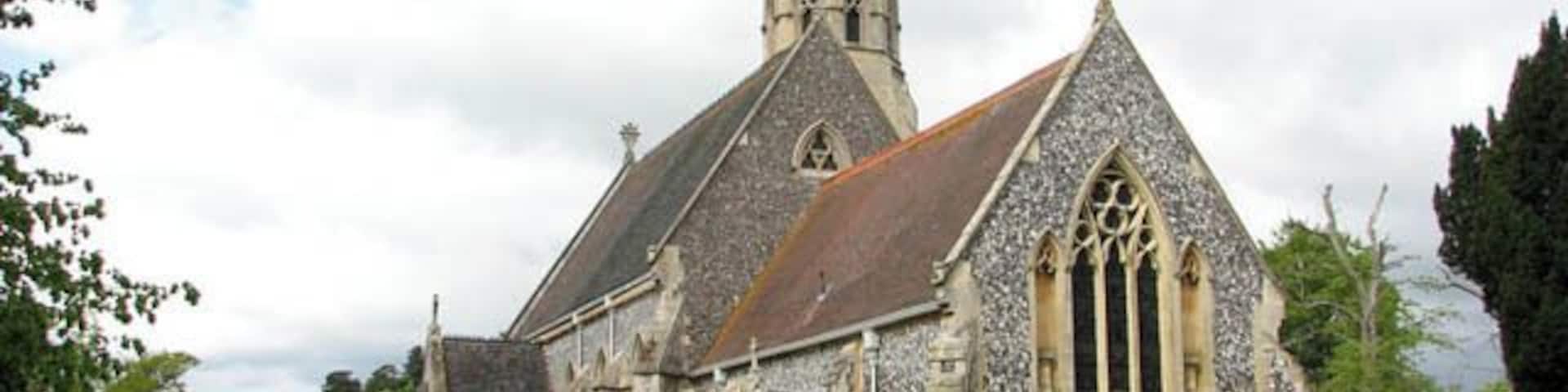 Una iglesia histórica con una aguja alta y arquitectura gótica, rodeada por un cementerio.