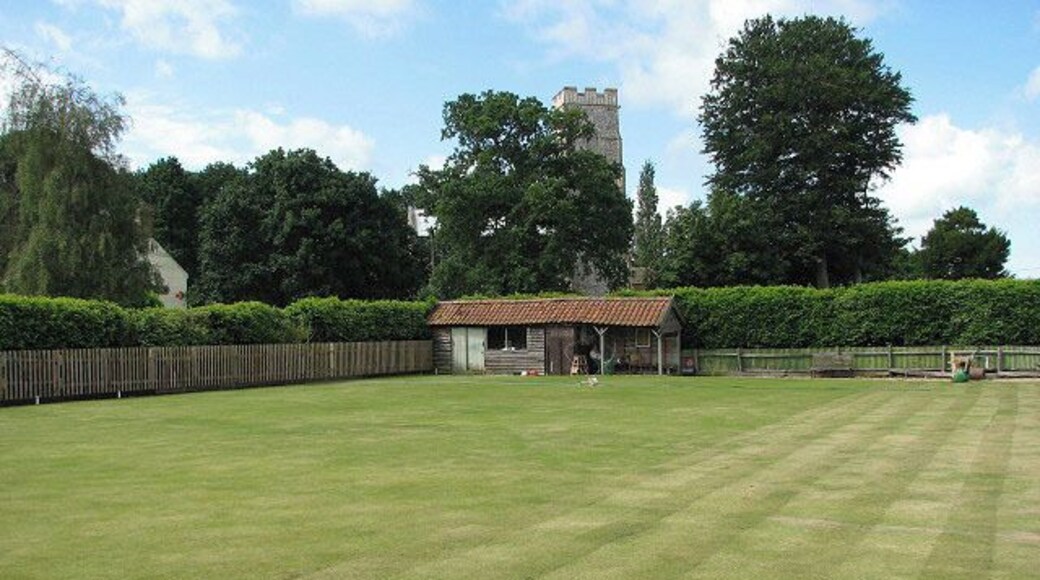 View to St Botholph's church across bowling green. The bowling green, surrounded by a hedge > 860872 on three sides, is located on the village green.