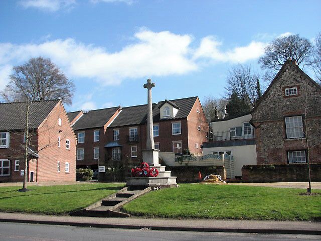 A residential area with brick houses, a central monument, and a grassy lawn.
