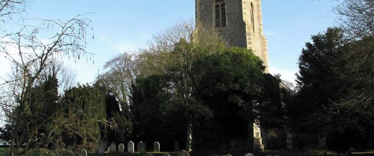 A church with a tall tower and a cemetery with headstones.