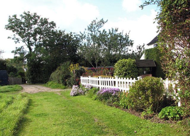 Path past cottage garden. The public footpath/access track which turns off Aylsham Road > 986043 runs past several properties set back from the road, here leading past a colourful border. It connects with The Street by the village hall > 986130 where it meets another path which leads north to the Community Primary School > 629777 in Youngman's Lane.