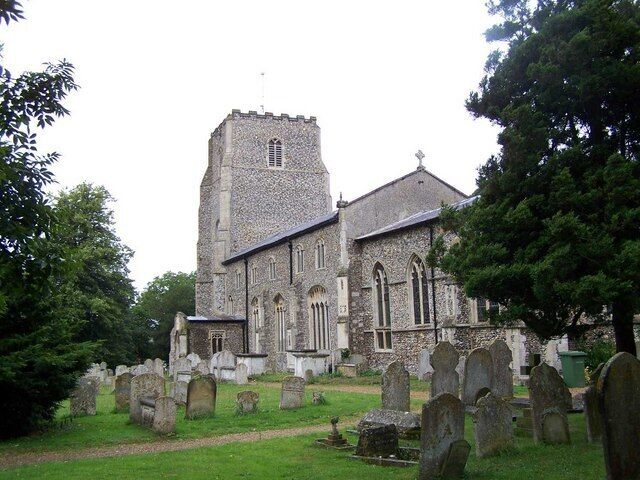 A church with a tall tower and a graveyard in front.