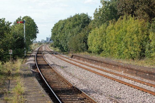 Reedham station photo-survey (4) Looking west - the up (Norwich-bound) direction - at Reedham station. The upper quadrant semaphore signal is on a tubular post. The long platforms at Reedham are no longer needed (most services are operated by three-car trains) so the up (west) ends of both have been fenced off and allowed to become overgrown as this shot shows. Reedham station is on the ex-Great Eastern Rly route from Norwich to Lowestoft and is situated roughly mid-way between the two towns. The station has two platforms, one for up (Norwich-bound) traffic and one for down (Yarmouth and Lowestoft) traffic. The majority of passenger services are operated by National Express. Half-a-mile east of the station is Reedham Junction; a single track route branches northeast to Yarmouth and the double track route continues southeast to Lowestoft. The junction is controlled by a traditional lever-frame signal box between the station and the junction itself.