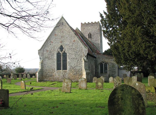 A stone church with a tower and a graveyard in front.