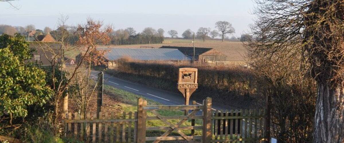 A rural road with a wooden gate and a signpost.