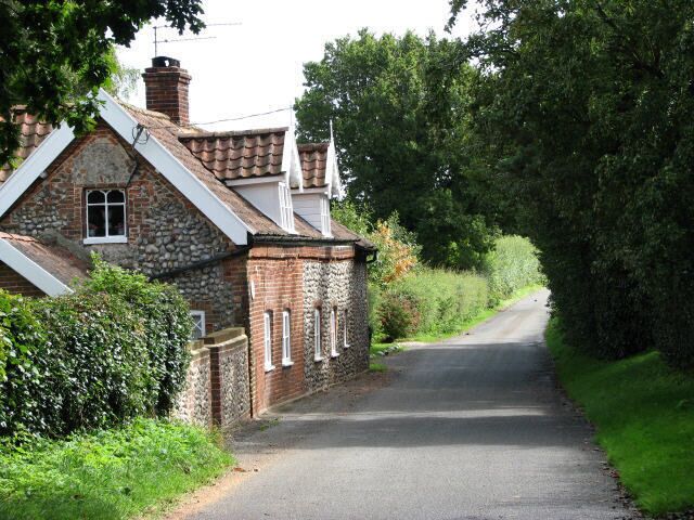 A narrow rural road flanked by stone houses with white window frames.