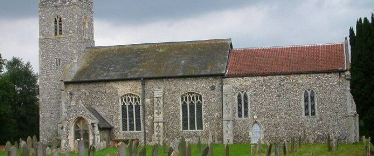 A stone church with a tower and a graveyard in front.