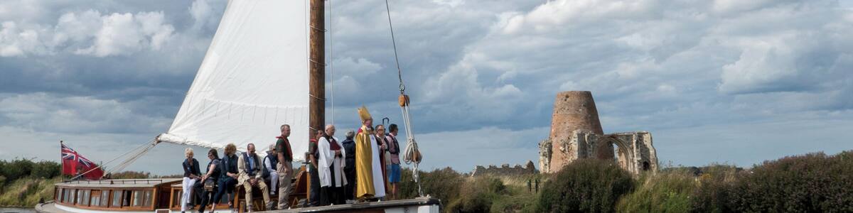 The The Rt Rev. the Lord Bishop of Norwich Graham James arrives on the wherry Ardea at St Benet's Abbey on 6 August 2017 for the annual service at the monastery ruins on the banks of the River Bure, Norfolk.