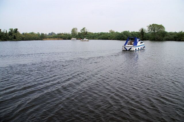 A river with a boat in the foreground and another in the background.