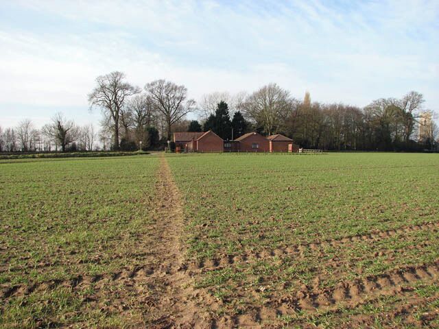 View west along path. This public footpath links Banningham Road with North Walsham Road, further to the east. The building seen in the background houses the Jubilee Hall and Sandy Lane Club. The tower of St Botolph's church > 860875 can be seen at right.