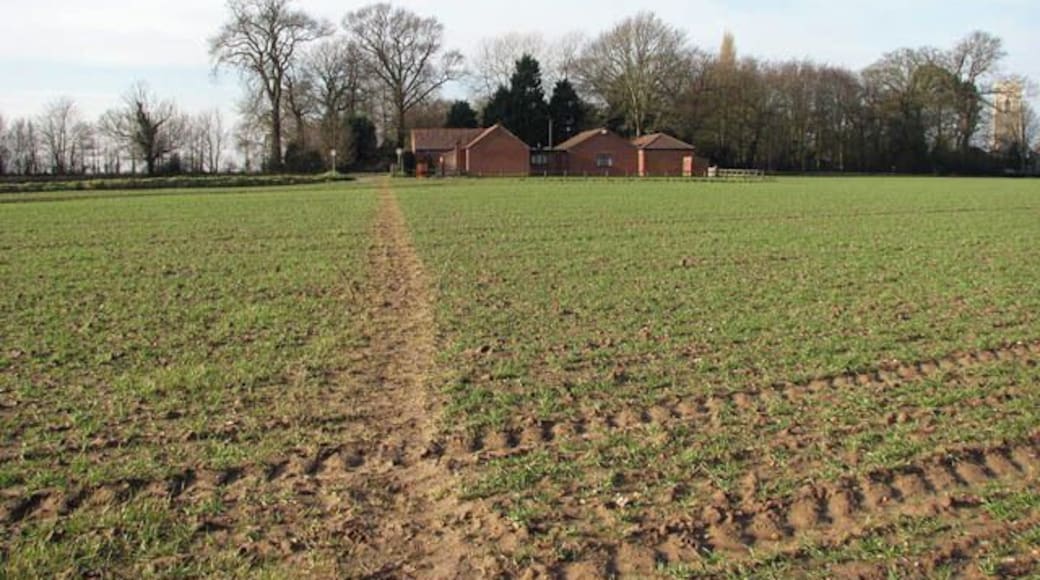 View west along path. This public footpath links Banningham Road with North Walsham Road, further to the east. The building seen in the background houses the Jubilee Hall and Sandy Lane Club. The tower of St Botolph's church > 860875 can be seen at right.