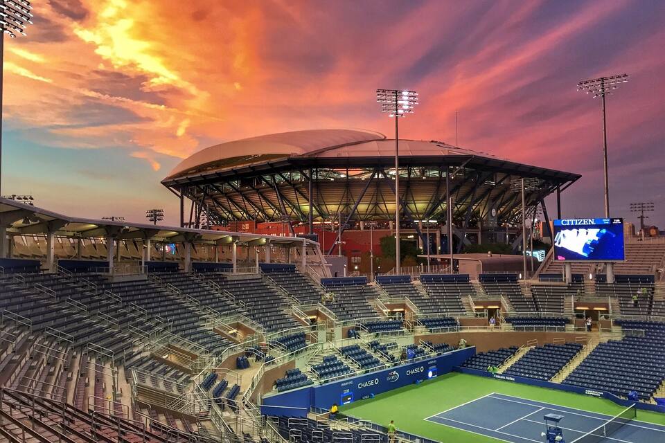 Un estadio grande con gradas vacías y una cancha de tenis.