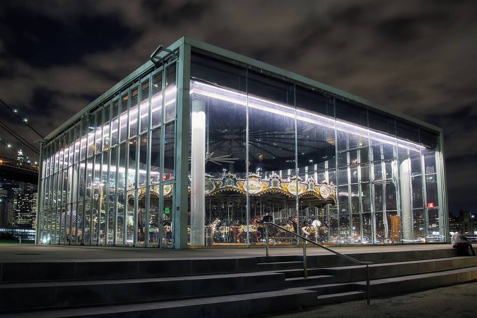 A modern building with large glass windows and a carousel inside.