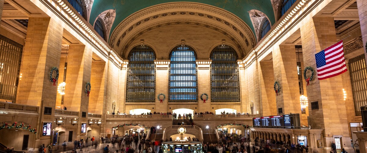 A large indoor public space with high ceilings, large windows, and a central staircase.