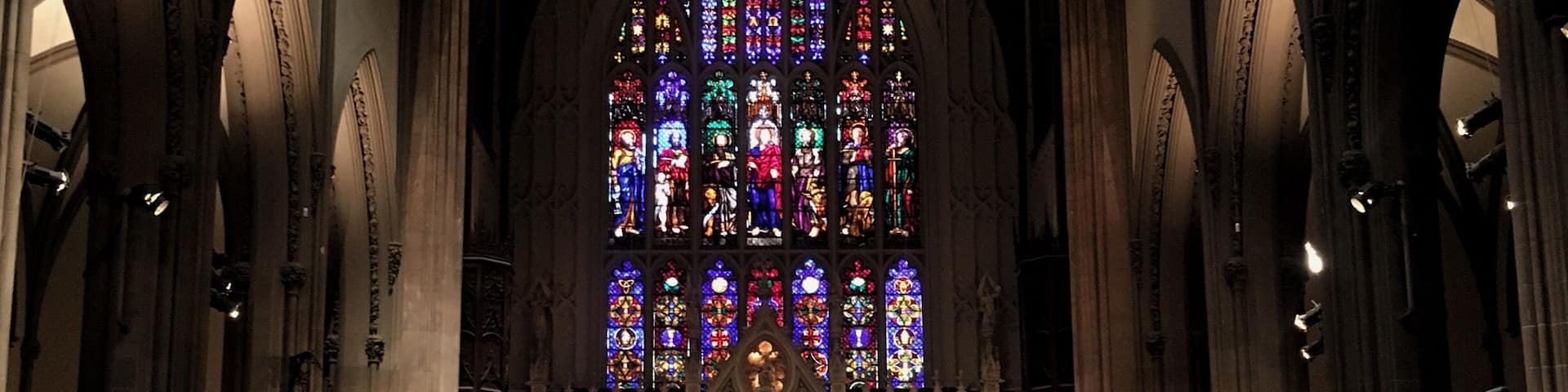 A cathedral interior with a large stained glass window and Gothic architecture.