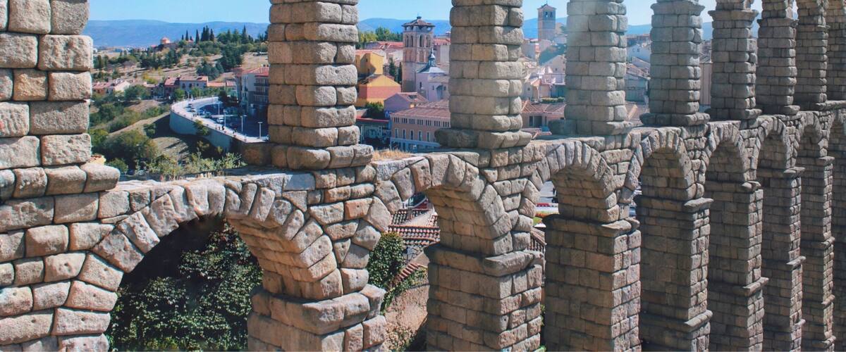 A stone aqueduct with arches overlooking a town.