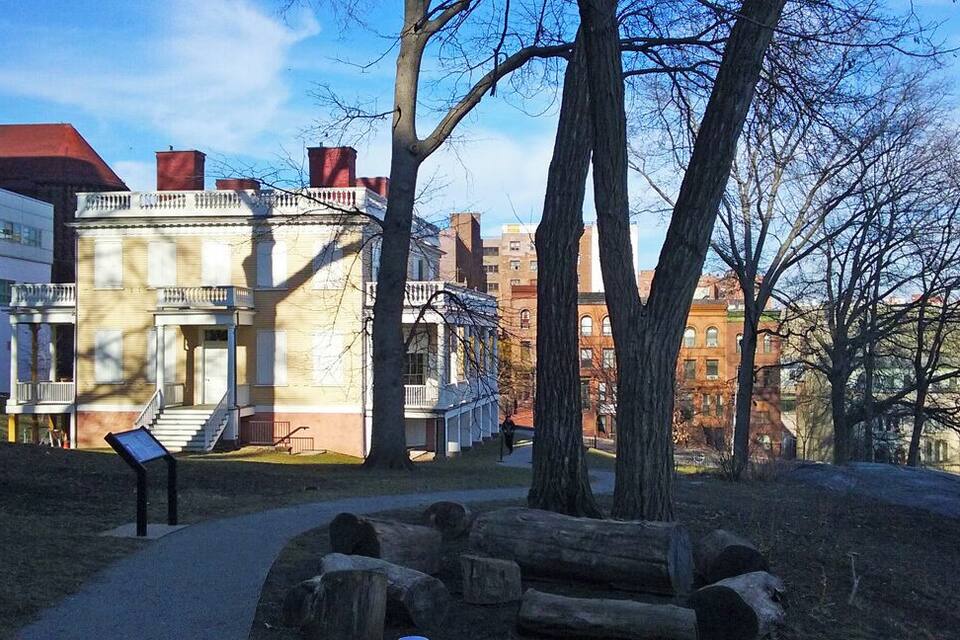 A historic building with a balcony, a pathway, and a sign.
