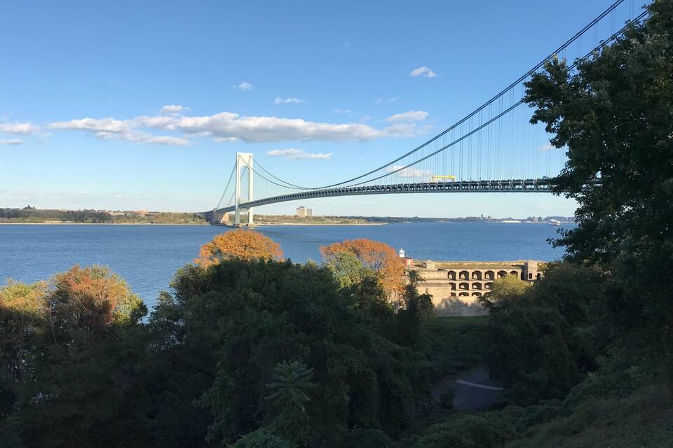 Un puente colgante sobre un río, con follaje otoñal en primer plano.