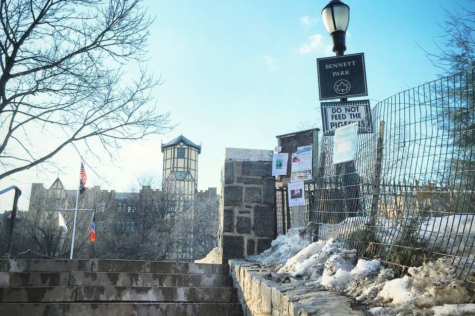 A staircase leading to a park entrance with a sign reading "Bennett Park" and a "Do Not Feed the Pigeons" sign.