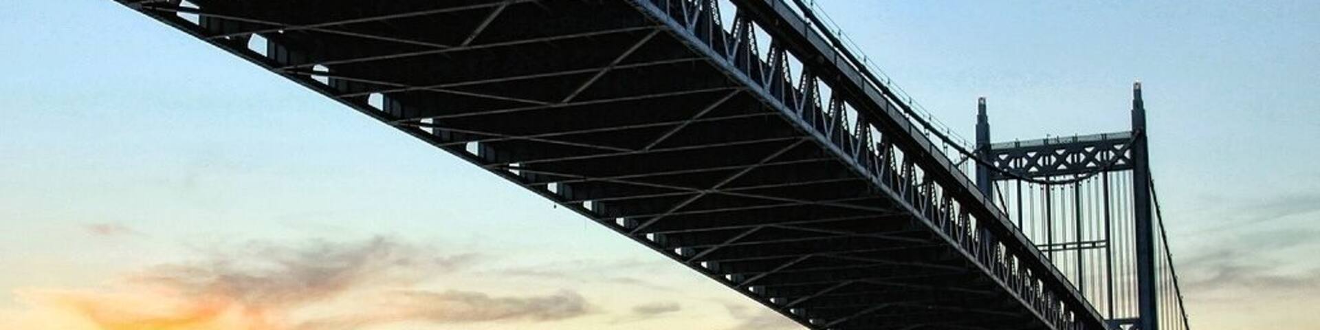 A bridge spanning a body of water with a sunset in the background.