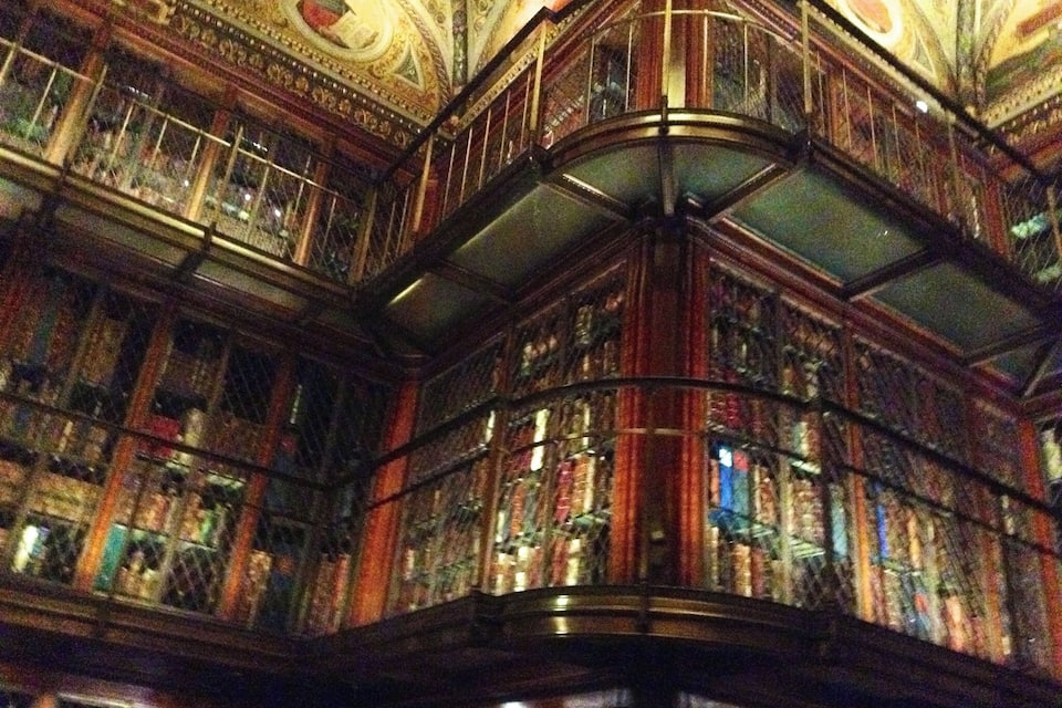 Eine prächtige Bibliothek mit aufwendigen Holzverzierungen und einem großen, runden Buntglasfenster.