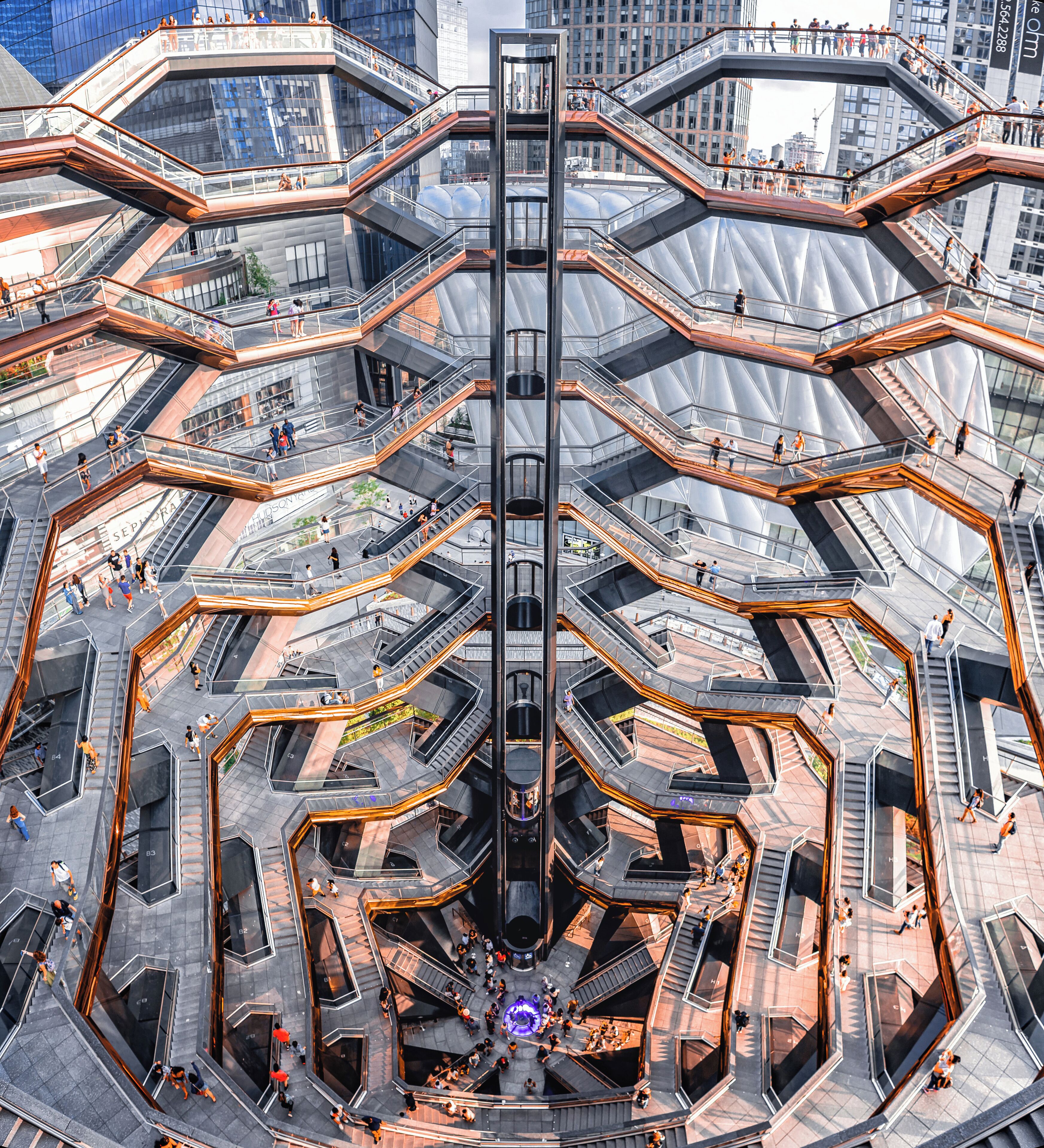 A complex, multi-level pedestrian bridge with glass railings and a central elevator shaft.