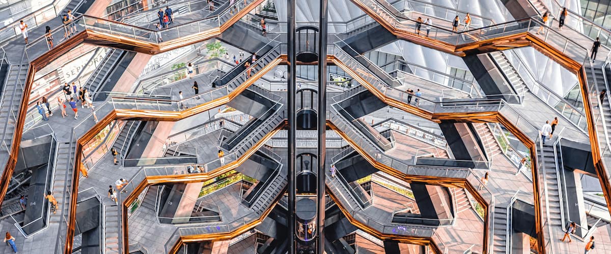 A complex, multi-level pedestrian bridge with glass railings and a central elevator shaft.