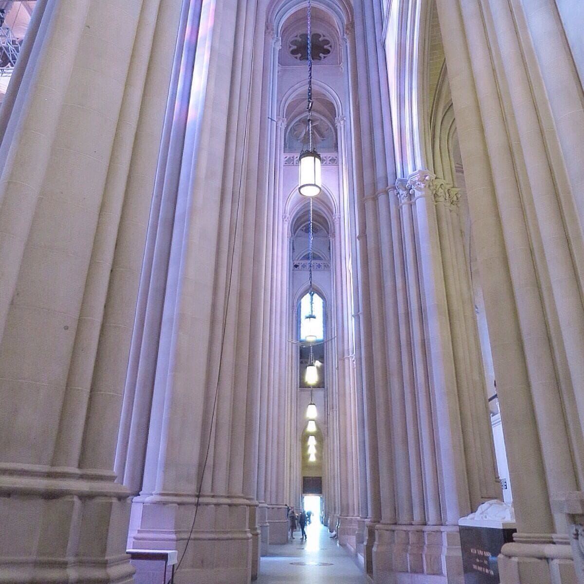 Columns inside Carhedral St John the Divine bathed in stained glass light 