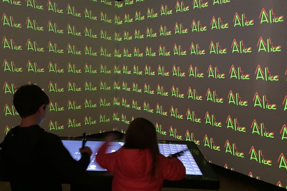 Proyección de la palabra 'Alice' repetida sobre una pared.