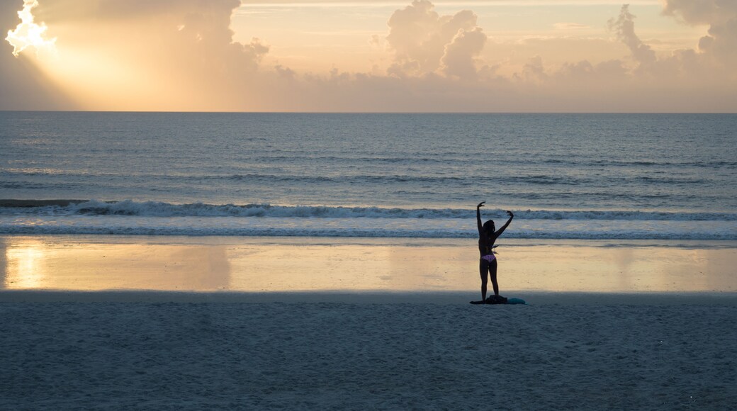 Unidentifiable african american woman relaxing at Jacksonville beach, looking at the sun going up at the sea. Beatiful sunrise