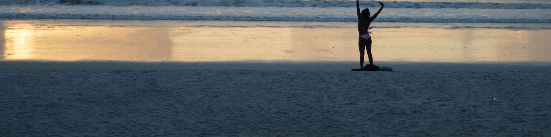 Unidentifiable african american woman relaxing at Jacksonville beach, looking at the sun going up at the sea. Beatiful sunrise
