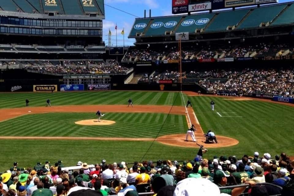 A baseball stadium with a scoreboard, advertisements, and a crowd of spectators.