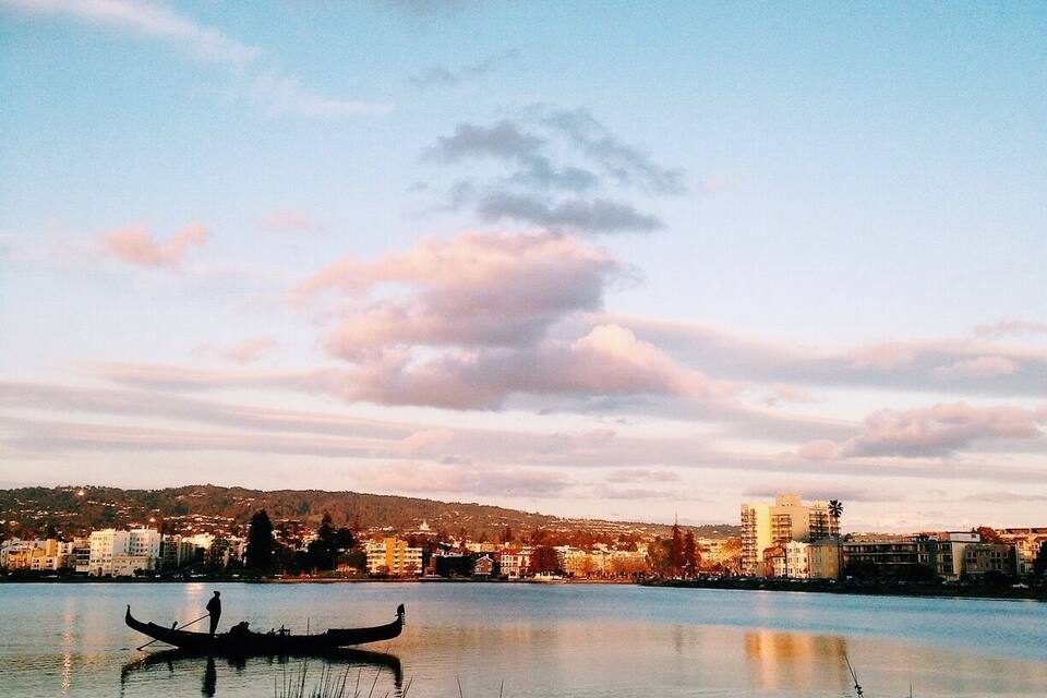 A calm lake with a gondola, buildings, and a clear sky.
