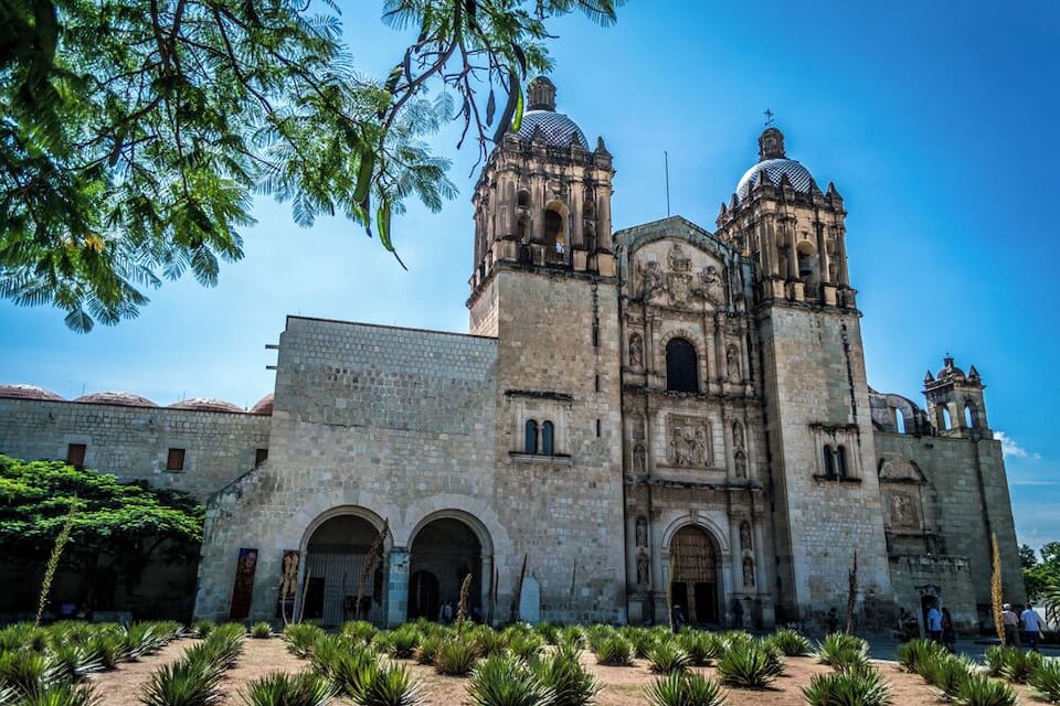Una catedral histórica con dos campanarios y un patio con palmeras.