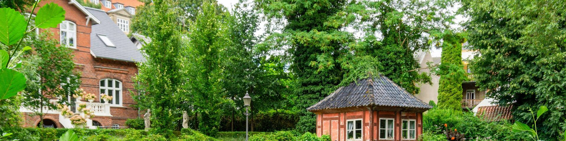 Picturesque Historic Timber Framed Pavilion on the Banks of the Odense River in Denmark Surrounded by Lush Gardens and Traditional Architecture