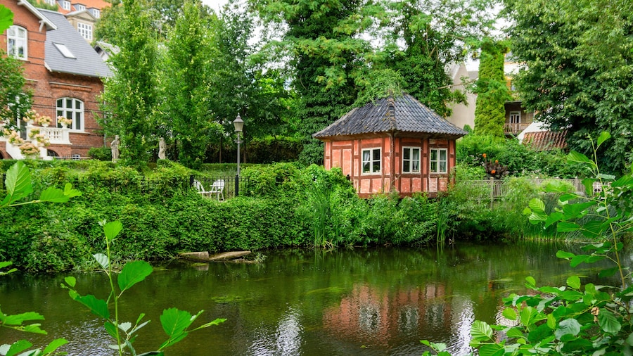 Picturesque Historic Timber Framed Pavilion on the Banks of the Odense River in Denmark Surrounded by Lush Gardens and Traditional Architecture