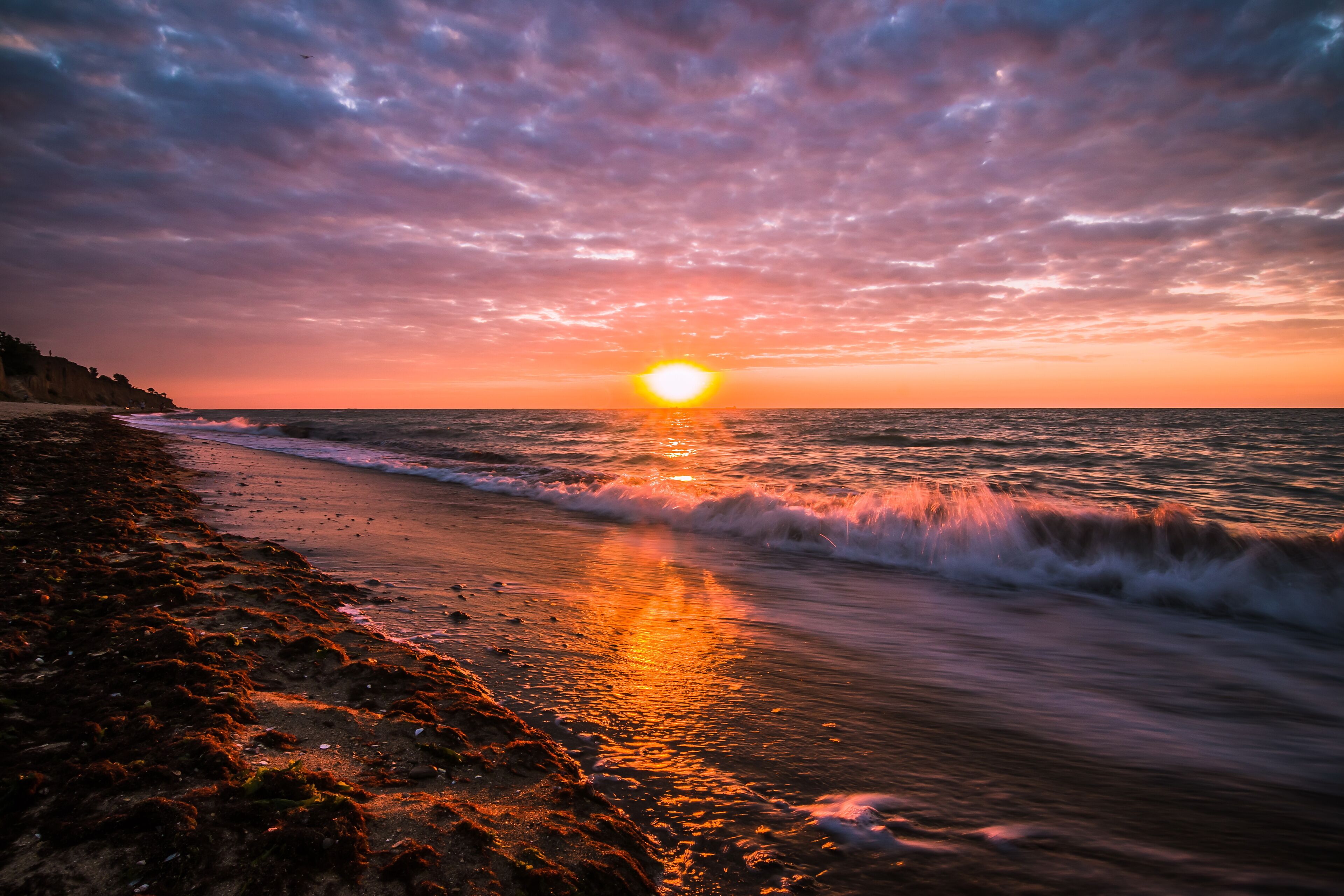 Beautiful sunrise at the sea on a cloudy morning. Ships can be seen against the background of sunrise on the horizon. Dropping off the sandy coastline. Black sea. Sanzhiika. Ukraine