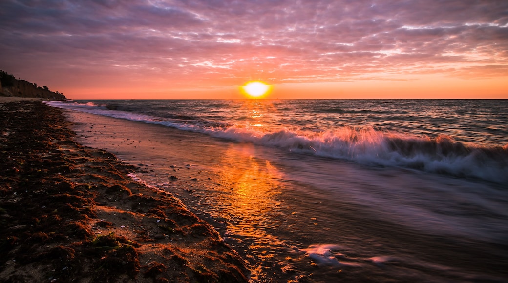 Beautiful sunrise at the sea on a cloudy morning. Ships can be seen against the background of sunrise on the horizon. Dropping off the sandy coastline. Black sea. Sanzhiika. Ukraine