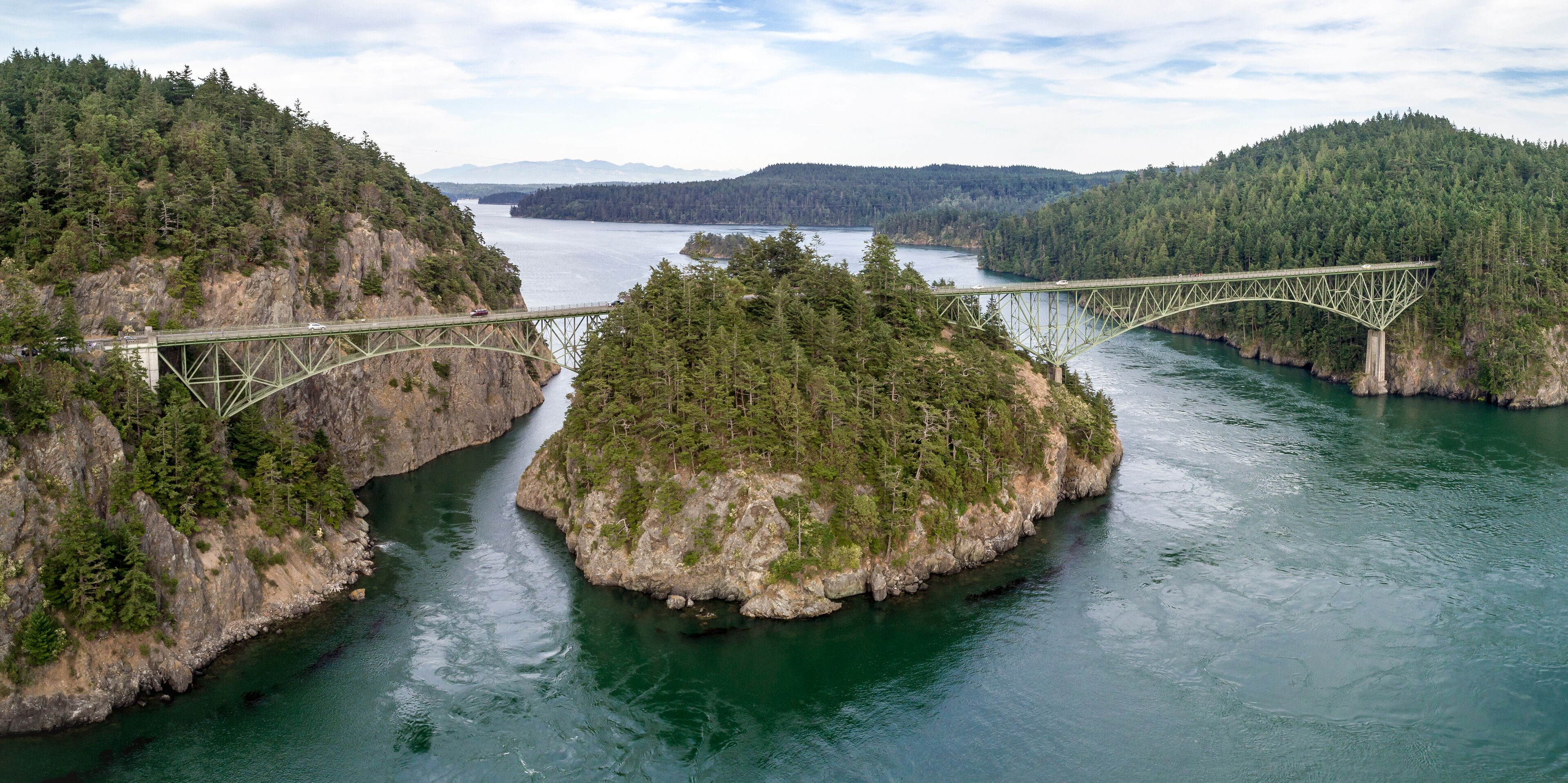 A bridge spanning a river over a forested island.